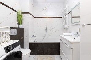 Un baño moderno con lavadora integrada, bañera y un inodoro.