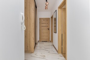 A hallway with a wooden door, a telephone, and a mirror on the wall.
