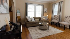 A living room with a sofa, two chairs, a coffee table, and a piano. - Modern 2BR Cottage | Pets Allowed Near Capitol (Montgomery)