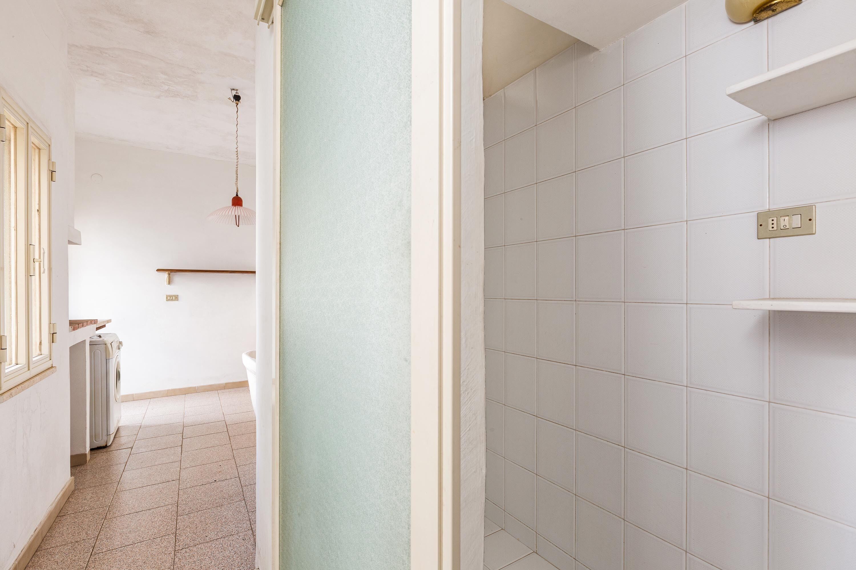 Een gang met een wasmachine, een radiator en een hanglamp.