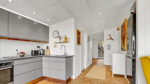 Una cocina moderna con armarios grises, suelo de parqué de madera y un horno empotrado, junto a una isla grande con un fregadero.