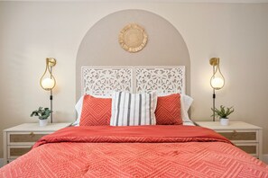Ein Schlafzimmer mit einem Bett, zwei Nachttischen, zwei Wandleuchten und Wanddekoration.