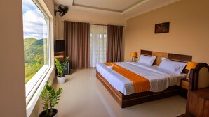 A hotel room with a large bed, a TV, a desk, and a window with curtains. - The Windy Mist Resort Munnar (Udumbanchola)