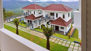 A two-story house with a red roof, white walls, and a balcony. - The Windy Mist Resort Munnar (Udumbanchola)