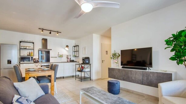 Un salon moderne avec un canapé, une table basse et un téléviseur.