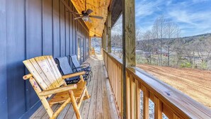 Una terraza de madera con dos sillas Adirondack y un ventilador de techo.