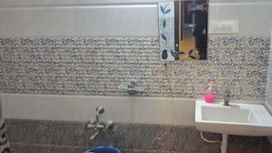 A bathroom with patterned tiles, a sink, and a mirror. - Hotel Pavan Mansion (Raichur)