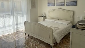A bedroom with a bed, a nightstand, a lamp, and artwork on the wall. - Spacious and bright family apartment (Sestri Levante)