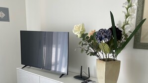 A modern living room with a flat-screen TV on a white cabinet, a decorative plant, and a router. - Spacious and bright family apartment (Sestri Levante)