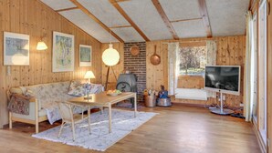 A cozy wooden cabin interior with a sofa, table, and TV.