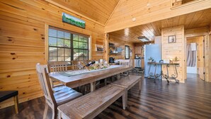 Ein Holzhütten-Interieur mit Esstisch, Bänken und einer Küchenzeile.