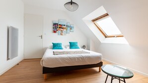 Une chambre à coucher avec un lit, une table en verre, un luminaire au plafond et une lucarne.