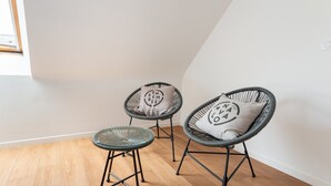 Une pièce comprenant deux fauteuils en osier et une petite table, chacun étant agrémenté d’un coussin.