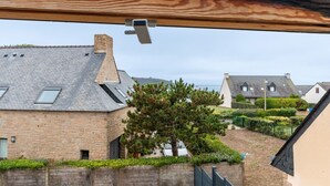 Un bâtiment en pierre avec un toit en pente, un arbre dans la cour et un ciel dégagé.