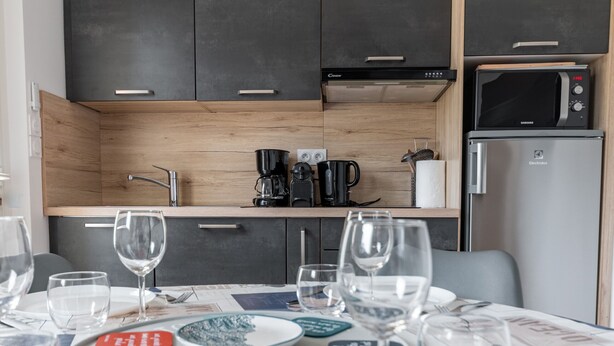 Une cuisine compacte dotée d’appareils électroménagers modernes, notamment une machine à café, un four à micro-ondes et un réfrigérateur.