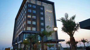 Un hotel moderno con un llamativo letrero 'SARA', varios pisos y una entrada bien iluminada con palmeras.