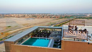 Zona de piscina en la azotea con un letrero que dice "SARA HOTEL" y vista panorámica de la ciudad de fondo.