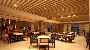 Un restaurante espacioso con techos altos, vigas de madera y diversas opciones de asientos, incluyendo mesas y sillas.