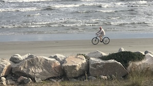 A beach with large rocks and a person riding a bicycle. - Oceanside, steps to the Beach, pets considered, cards avail, Beach Club Complex (Saint Helena Island)