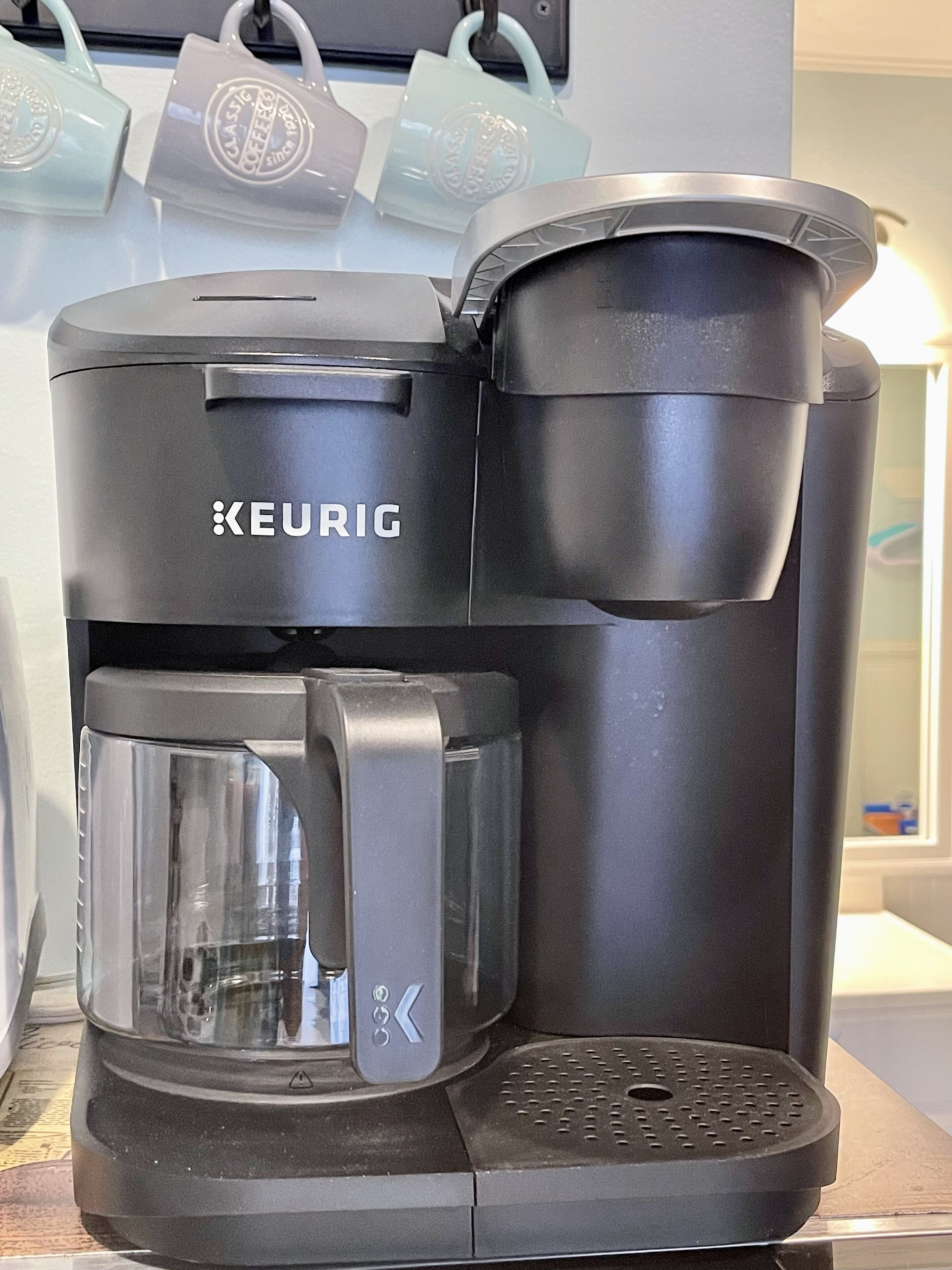 Een Keurig koffiezetapparaat met een kan en een lekbak.