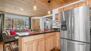 A modern kitchen with wooden cabinets, a stainless steel refrigerator, and a granite countertop.
