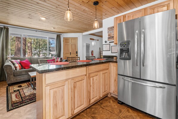 Una cocina moderna con armarios de madera, un refrigerador de acero inoxidable y una encimera de granito.