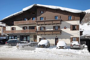 A multi-story hotel with balconies, a snow-covered roof, and parked cars.