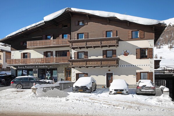 A multi-story hotel with balconies, a snow-covered roof, and parked cars.
