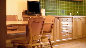 A kitchen with wooden cabinets, a green tiled backsplash, and a television on a stand. - Apartment "Casa San Marco N 1" with Mountain View, Garden & Wi-Fi (Livigno)