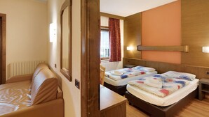 A room with a bed, a sofa, a wooden headboard, a window with curtains, and a wall-mounted light. - Apartment "Casa San Marco N 1" with Mountain View, Garden & Wi-Fi (Livigno)