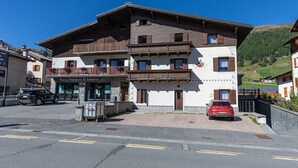Un bâtiment à deux étages doté d’un balcon, d’une enseigne indiquant « Banca Popolare di Sondrio », et d’une voiture rouge garée devant.