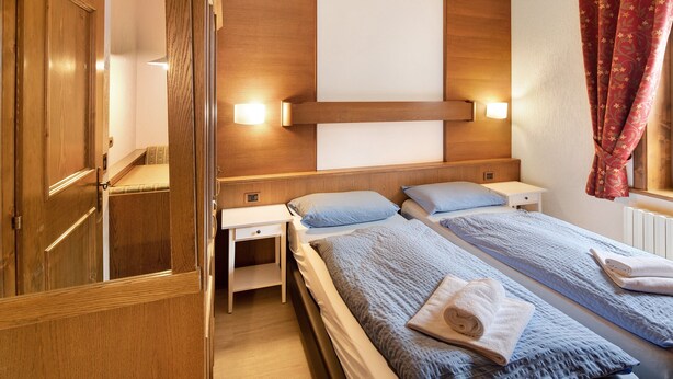 Une chambre d’hôtel avec deux lits, une tête de lit en bois, des tables de chevet et une armoire.
