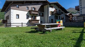 Un chalet traditionnel avec un banc en pierre, une terrasse en bois et une vue imprenable sur les montagnes.