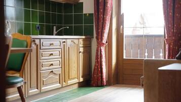 A kitchen with wooden cabinets, a green tiled backsplash, and a window with a view.