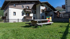 Ein traditionelles Chalet mit einer Steinsitzbank, einer Holzdielenveranda und einem Blick auf die Berge.