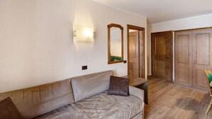 Ein Zimmer mit einer Couch, einem Spiegel, Holztüren und einer Lampe.
