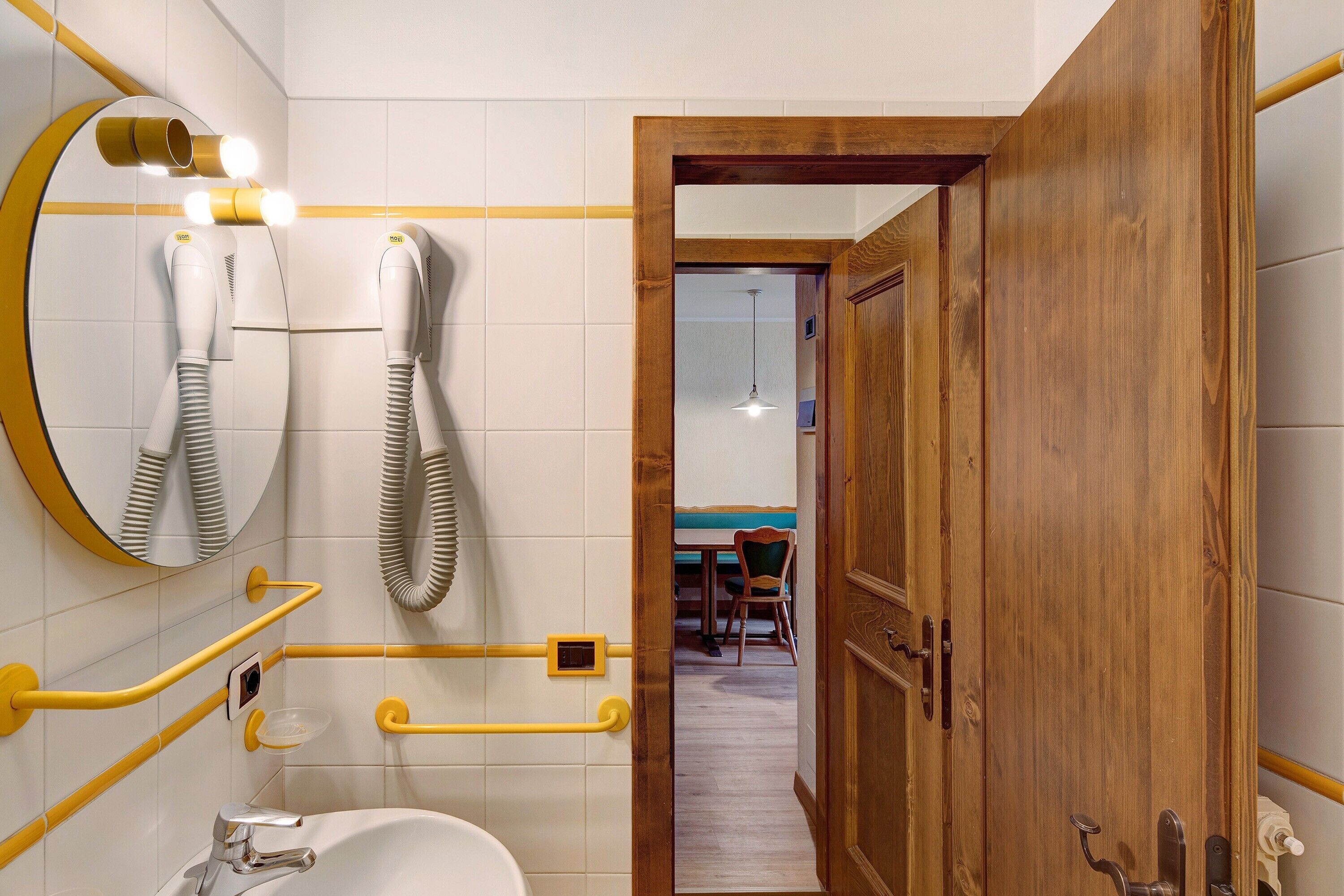 Une salle de bain équipée d’un miroir, d’un sèche-cheveux et de barres d’appui.