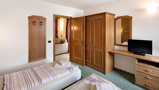 A bedroom with two beds, a wardrobe, a desk with a TV, and a mirror. - Holiday Apartment "Casa San Marco n 5" with Mountain View, Balcony & Wi-Fi (Livigno)