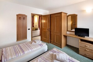 Un dormitorio con dos camas, un armario, un escritorio con televisor y un espejo.