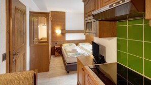 A compact kitchen with wooden cabinets, a microwave, and a green tiled backsplash. - Holiday Apartment "Casa San Marco n 6" with Mountain View, Balcony & Wi-Fi (Livigno)