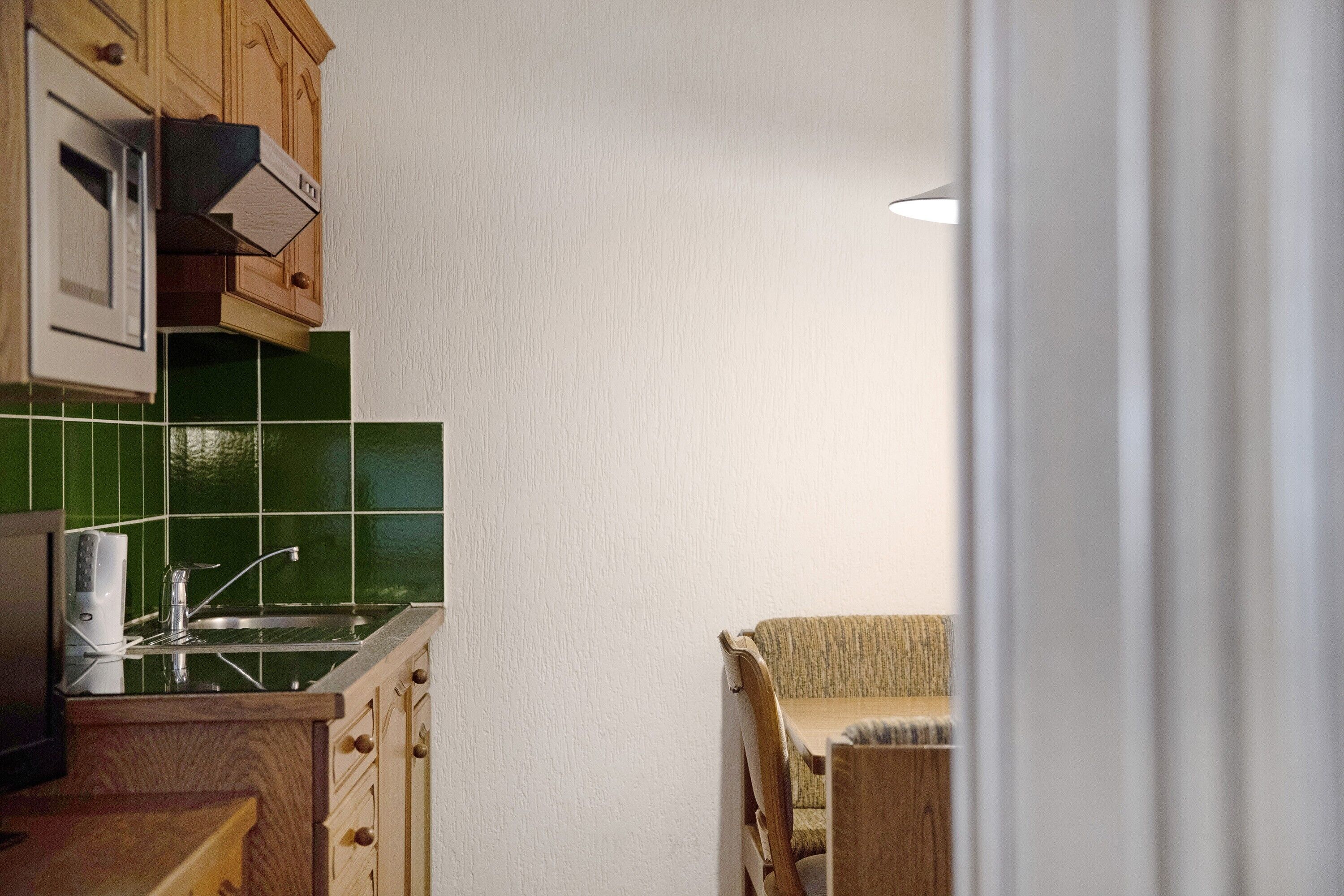 Une cuisine équipée d’un four à micro-ondes, d’un évier et de meubles de rangement en bois.