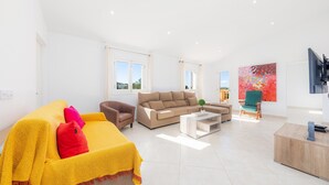 Ein modernes Wohnzimmer mit einer Couch, einem Sessel, einem Couchtisch und einem Fernseher.