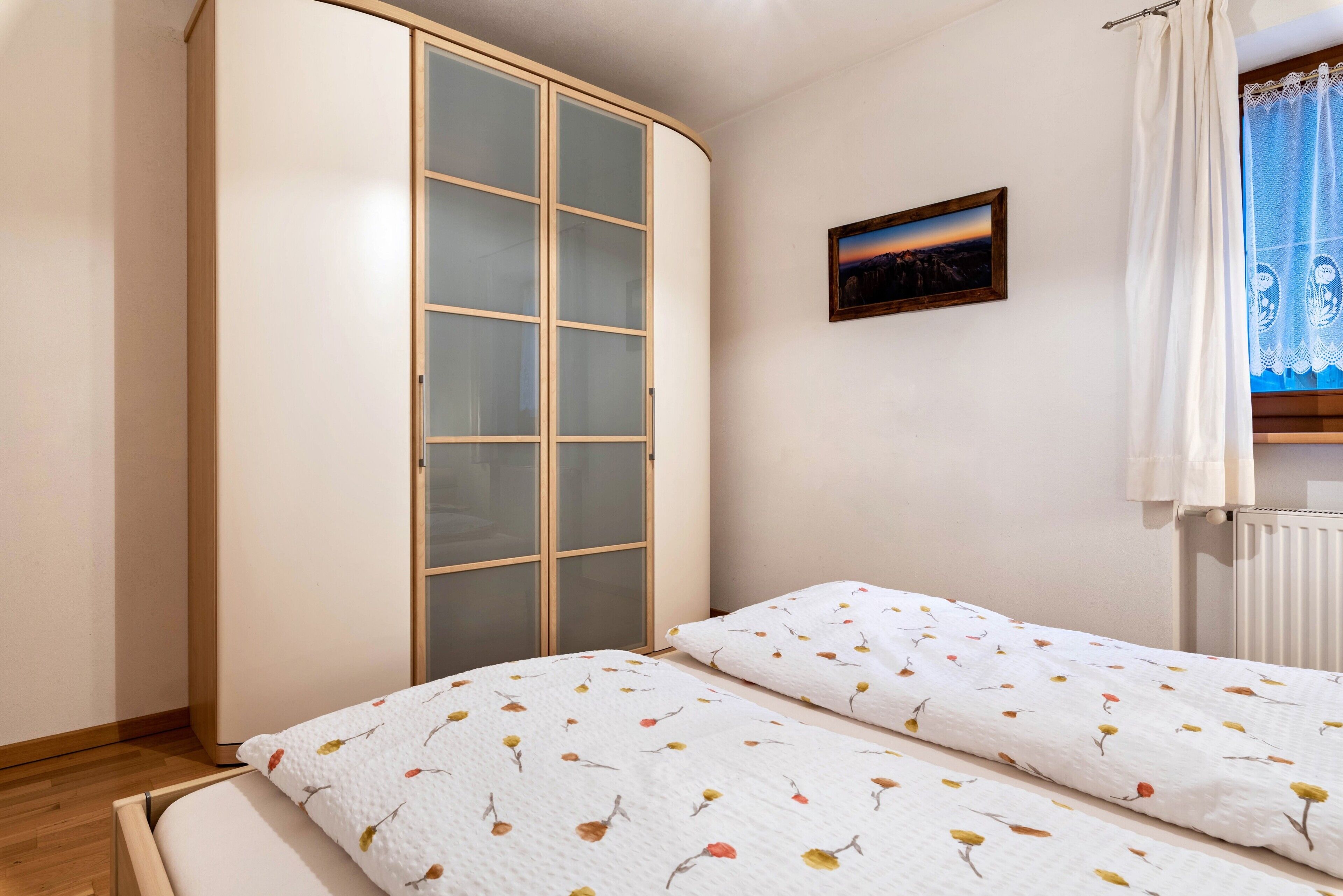Ein Schlafzimmer mit einem Bett, einem Kleiderschrank und einem Fenster mit Vorhängen.