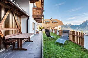 Une façade en bois avec un banc et des chaises, un espace patio et une vue sur les montagnes.