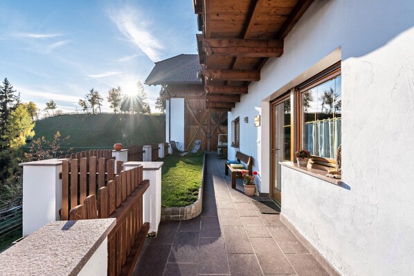 Un espace extérieur abrité, doté d’une terrasse en bois, d’un chemin en pierre et d’une petite pelouse.