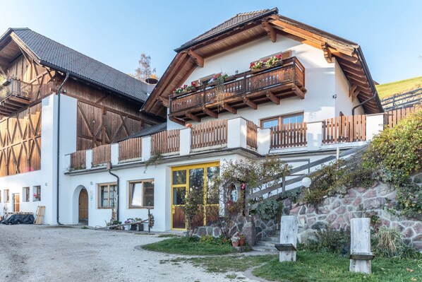 A traditional chalet with a stone facade, wooden balconies, and a gravel driveway.