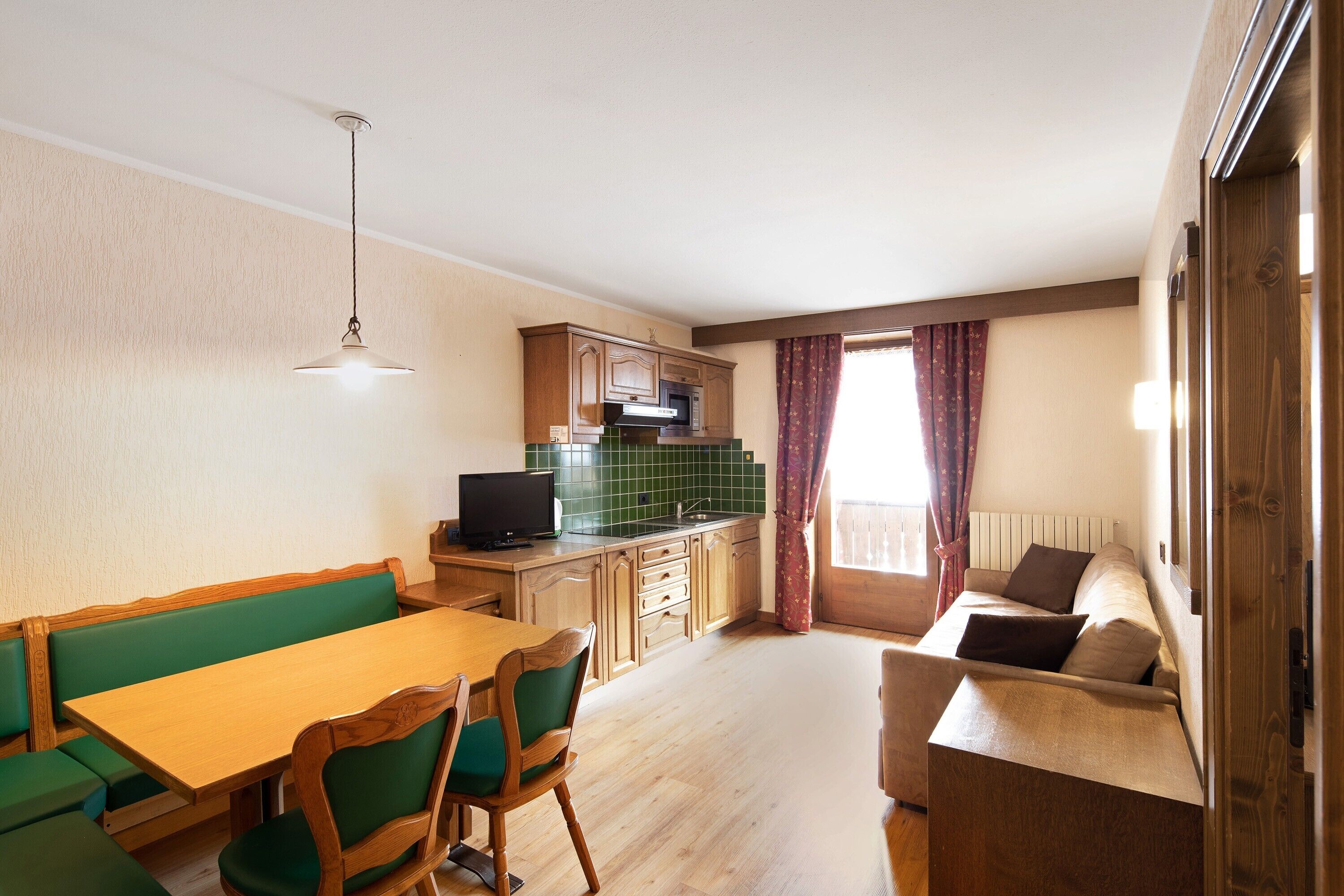 A compact living space with a dining area, kitchenette, and a sofa.