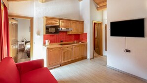A modern kitchen with wooden cabinets, a red backsplash, and a built-in microwave. - Holiday Apartment "Casa Marcos n 29" with Mountain View, Balcony & Wi-Fi (Livigno)