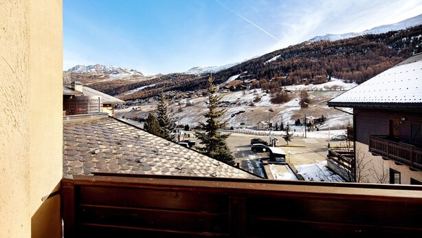 A mountain view from a balcony with a tiled roof, a wooden railing, and a clear sky. - Holiday Apartment "Casa Marcos n 31" with Mountain View, Balcony & Wi-Fi (Livigno)