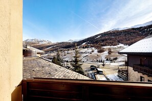 Une vue sur la montagne depuis un balcon doté d’un toit en tuiles, d’une balustrade en bois et surplombant un ciel dégagé.